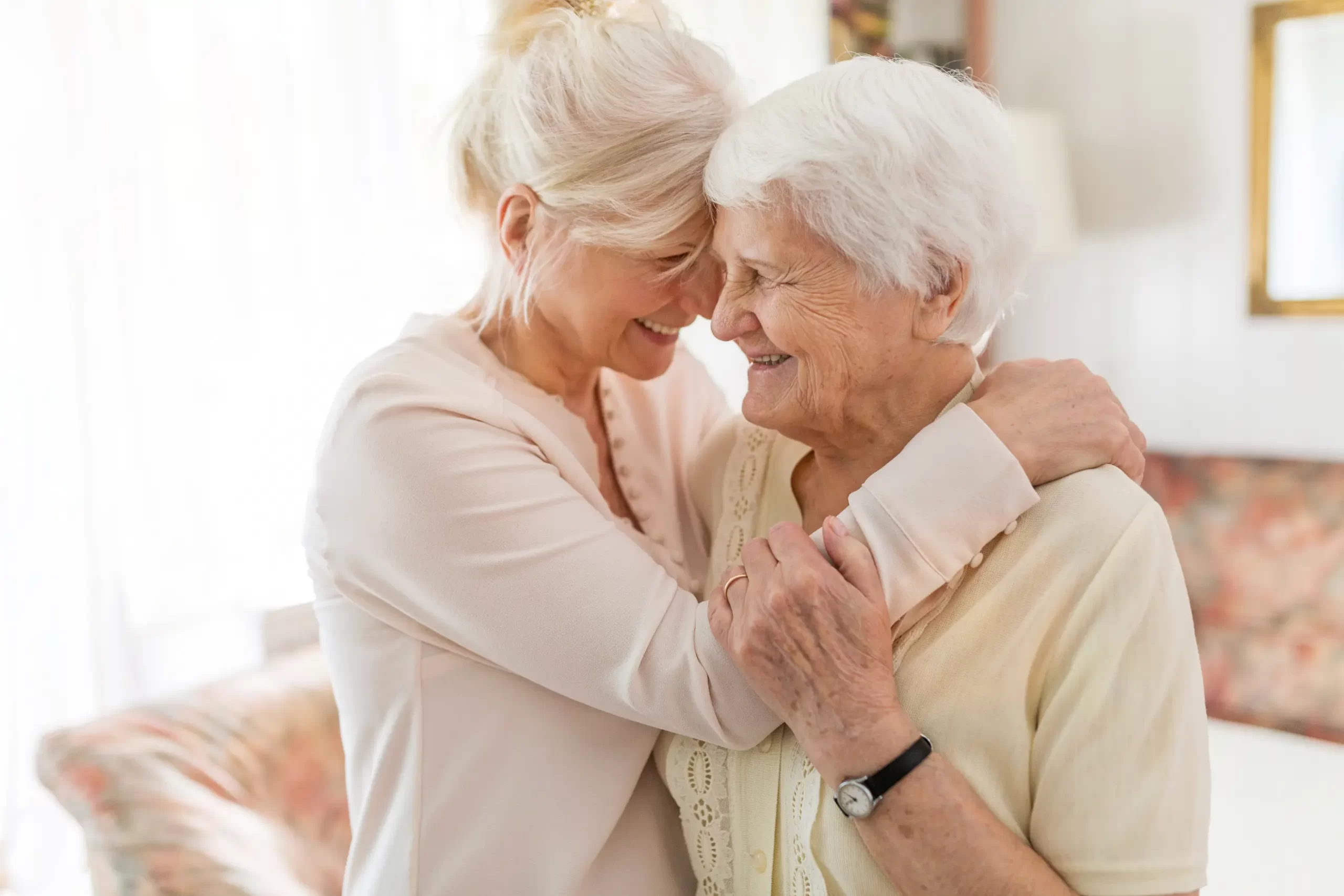 Eine Dame umarmt eine Seniorin und ist dabei glücklich. In diesem Zusammenhang ist das Bild was zu sehen ist, mit der 24 Stunden Pflege verbunden.